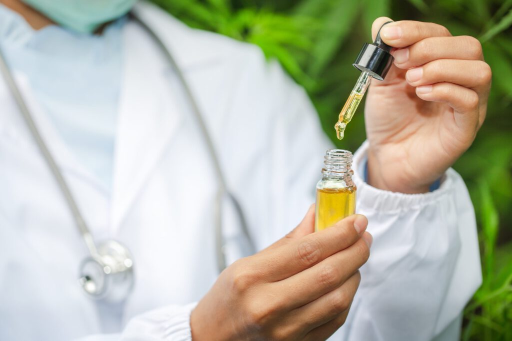 Medico che utilizza un contagocce per dosare olio di CBN®, rimedio naturale derivato dalla cannabis, in un ambiente verde.