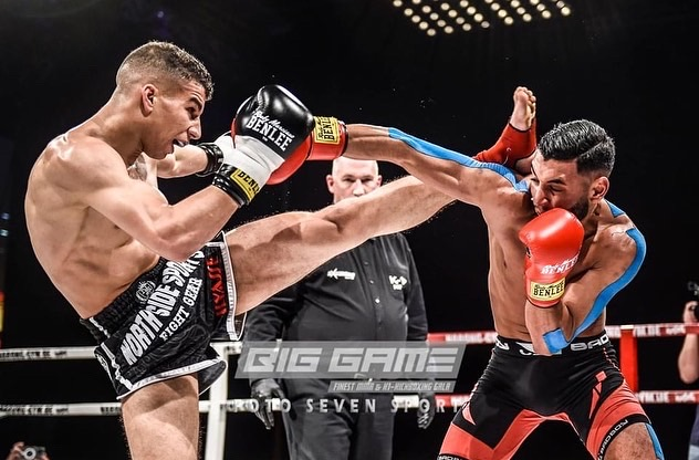 Ilyasse Koujjit, kickboxer marocchino del Team Gunyar, in azione sul ring mentre sferra un calcio al suo avversario che tenta un jab corto.